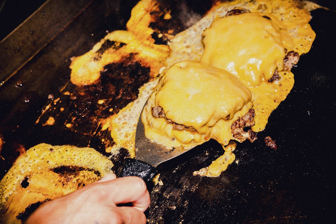 Smash burgers cooking on a flat top griddle with crispy edges
