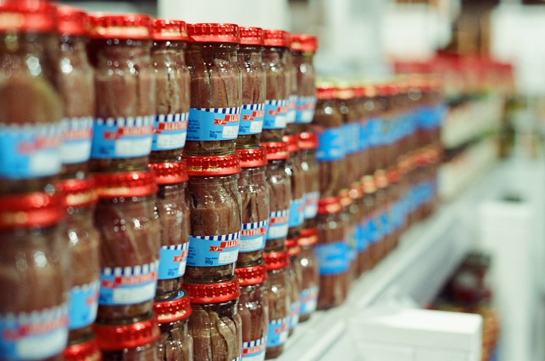 Glass jars of preserved food lined up on a pantry shelf