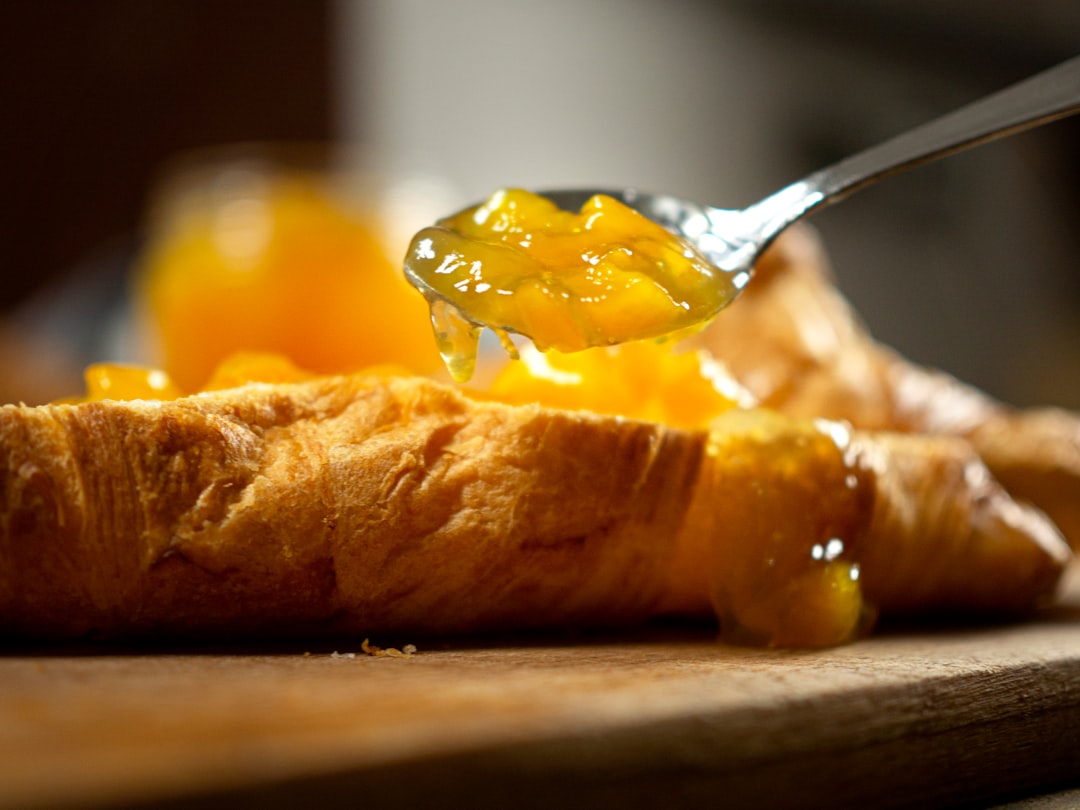 Homemade peach jam being scooped with a wooden spoon