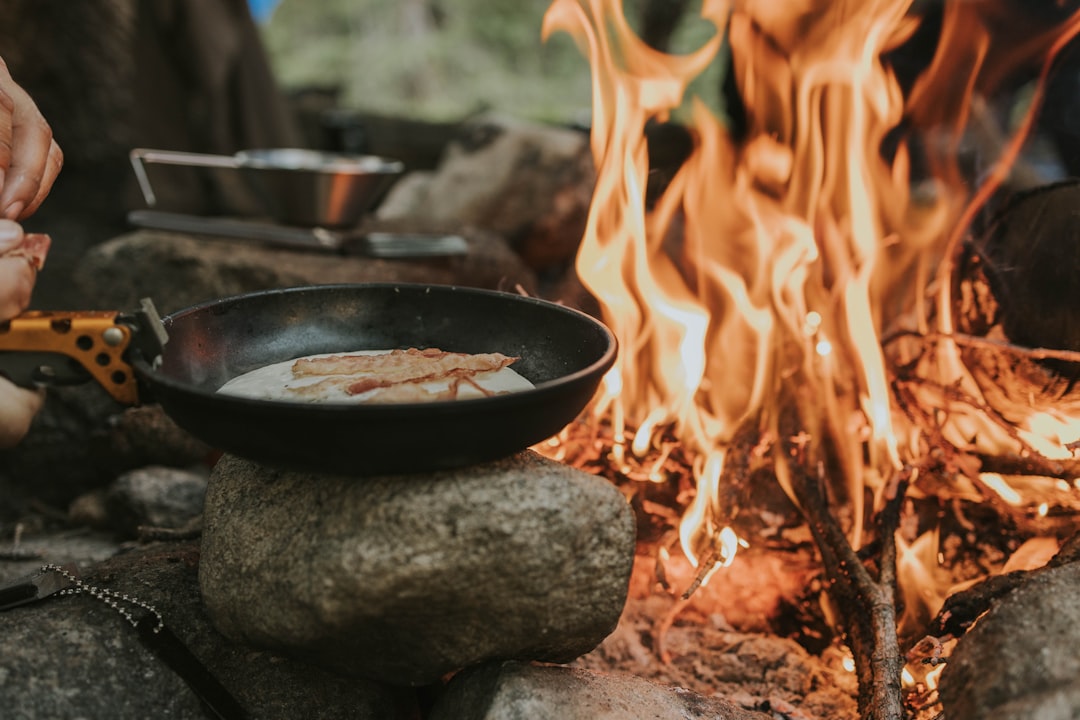 Cast iron skillet cooking over an outdoor campfire