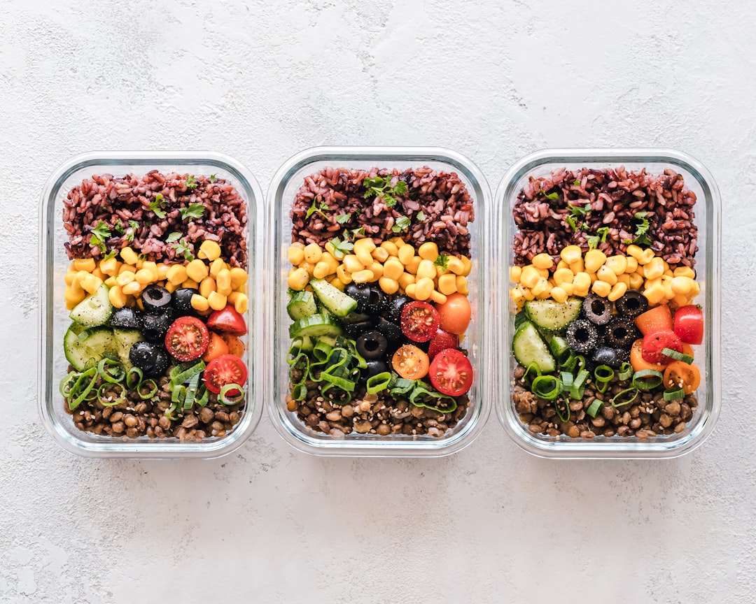 Glass meal prep containers filled with fresh food, lined up in the refrigerator