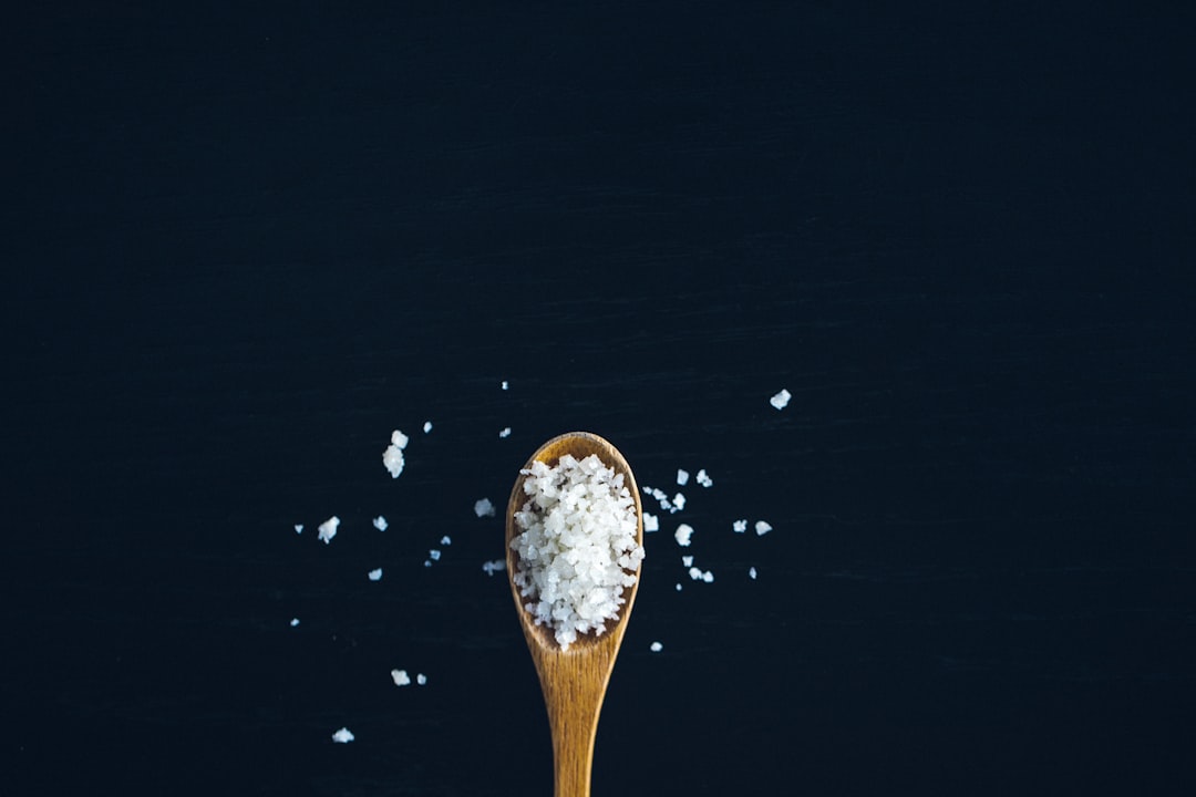 Flaky sea salt crystals holding their shape on a wooden spoon