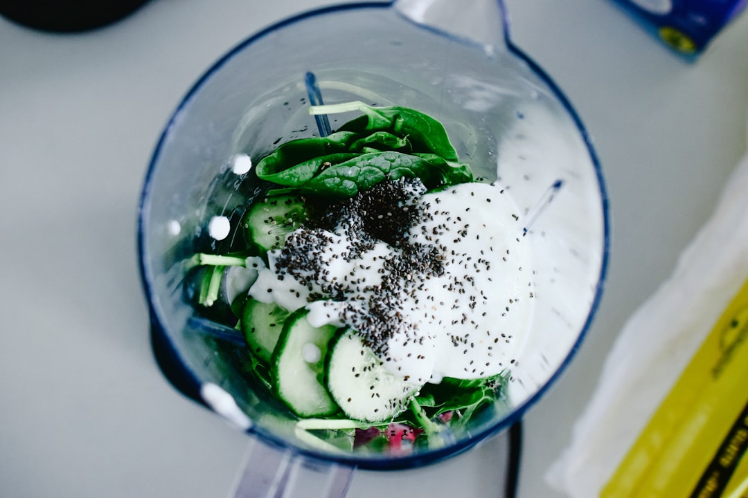 Green smoothie surrounded by fresh spinach and fruit
