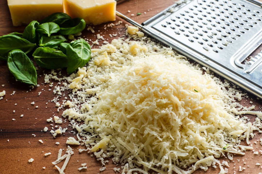 A pile of freshly grated parmesan with a grater and basil
