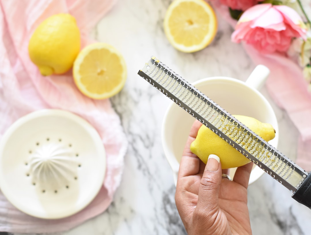 Hand pressing a lemon half with a squeezer to add fresh acid to a dish