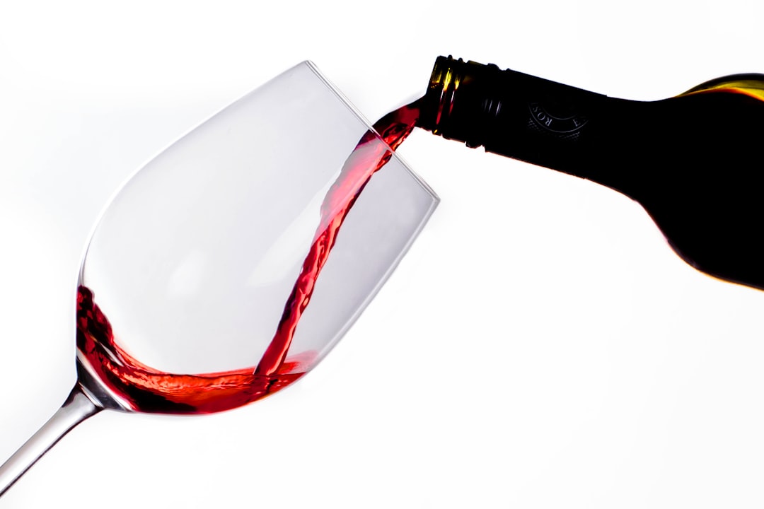Red wine being poured into a hot pan to deglaze the fond