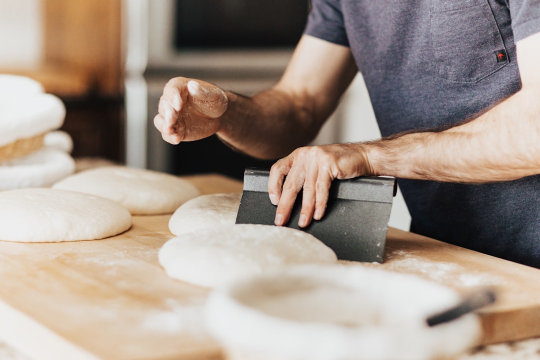 Hands using a bench scraper to shape dough on a floured counter