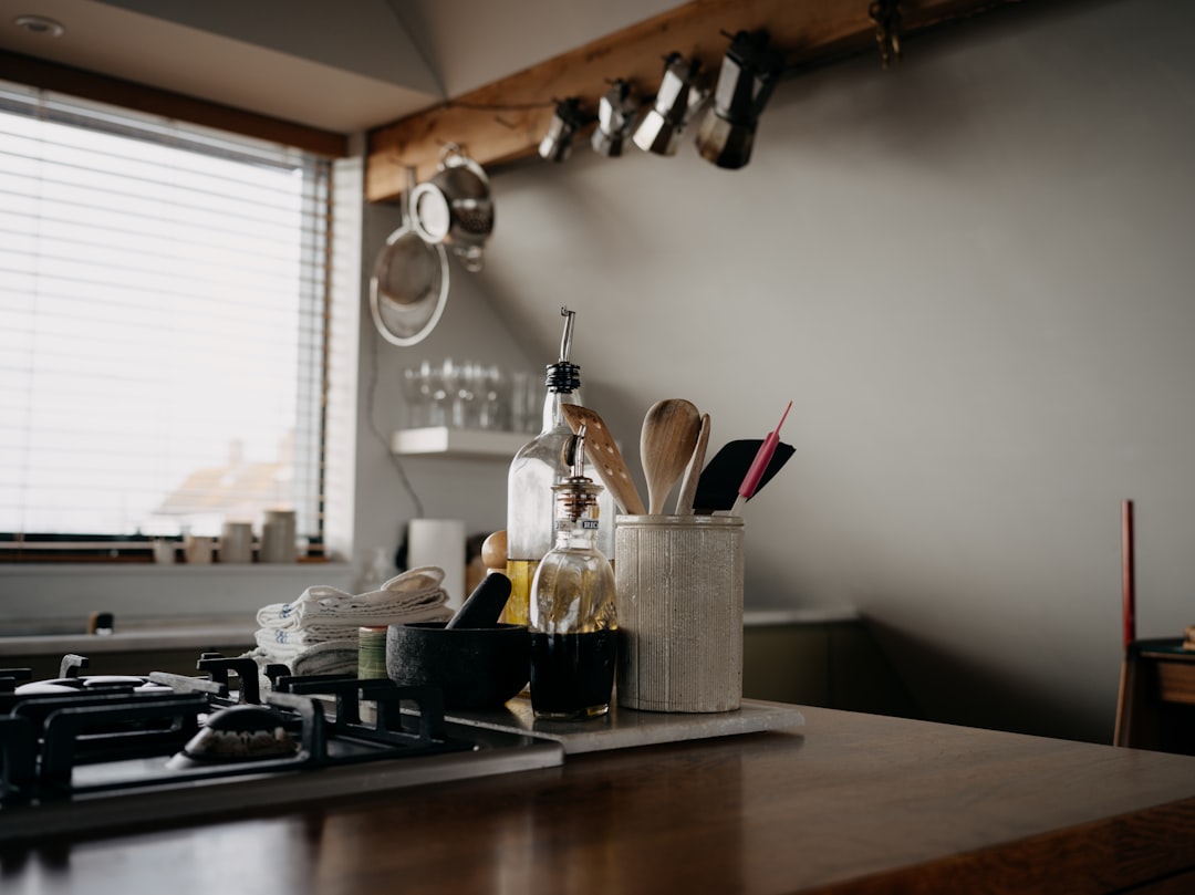 Wooden utensils beside oil bottles on a kitchen counter