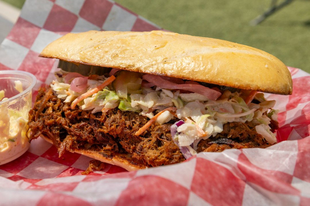 Pulled pork sandwich piled with coleslaw on checkered paper