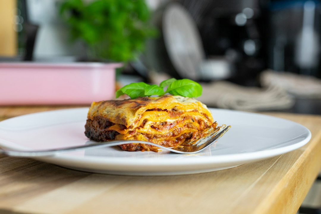 A slice of lasagna served on a plate at a wooden table