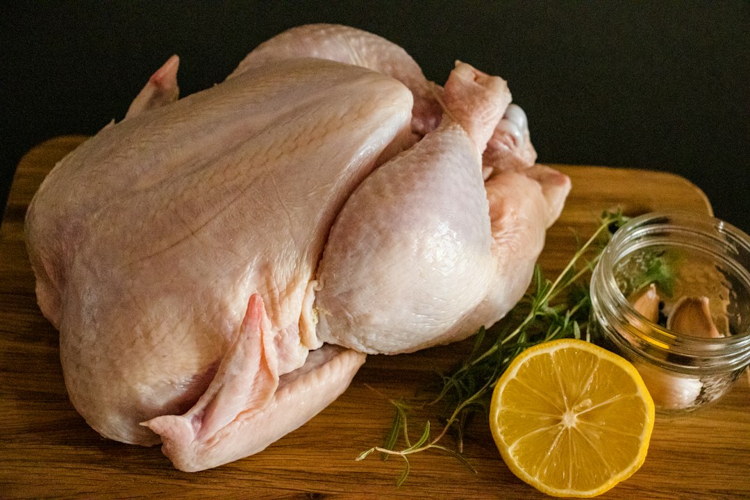 Whole raw chicken prepped with lemon, garlic, and herbs before braising