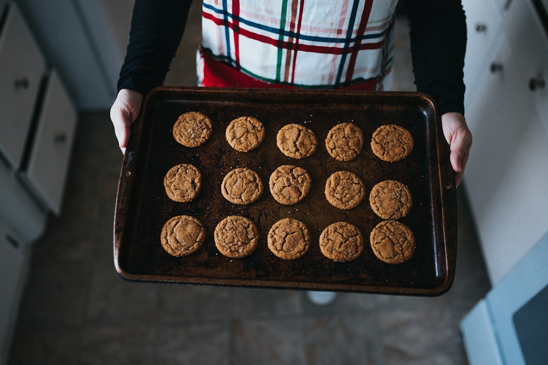 Hands holding a baking tray full of freshly baked cookies