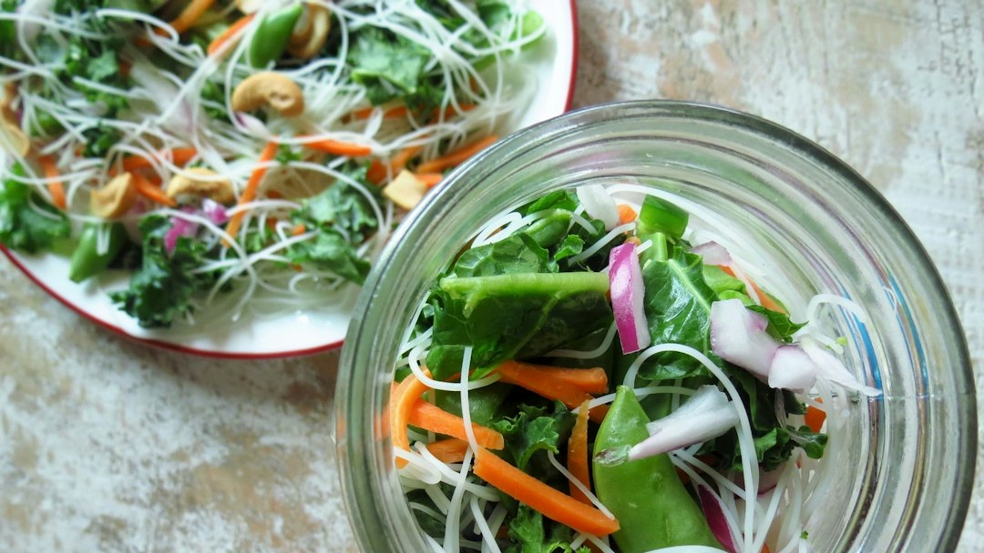 Glass mason jar filled with layers of salad greens and vegetables