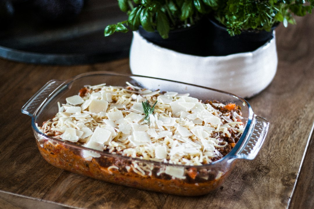 Lasagna baking in a clear glass dish topped with melted cheese