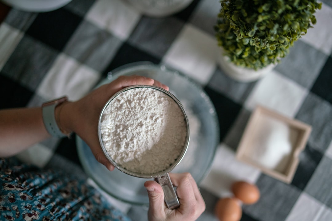 Hands measuring flour over a mixing bowl