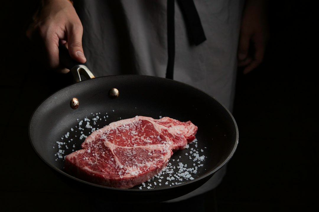 Beef searing in a cast iron pan with seasonings