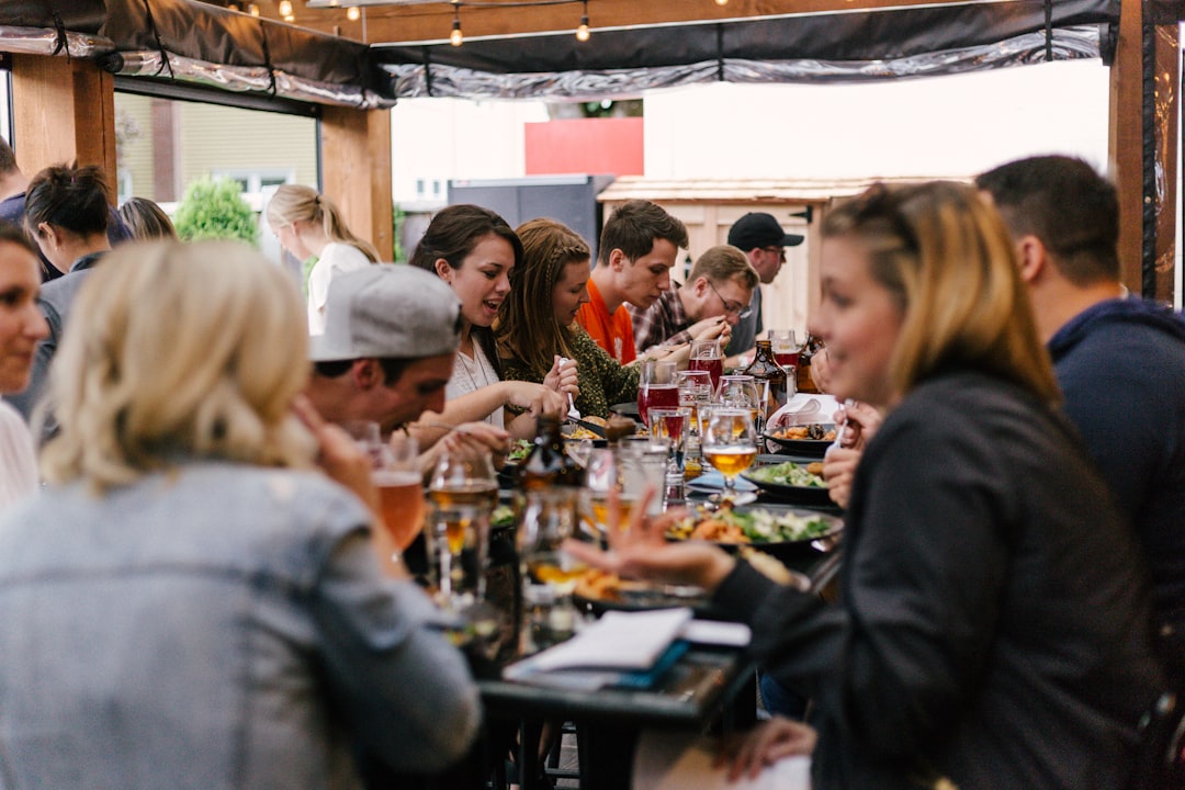 Friends laughing together over a long table sharing a meal, the whole point of a raclette night