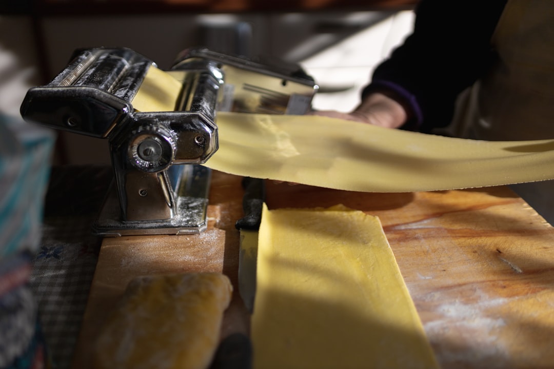 Pasta roller machine flattening a sheet of fresh dough