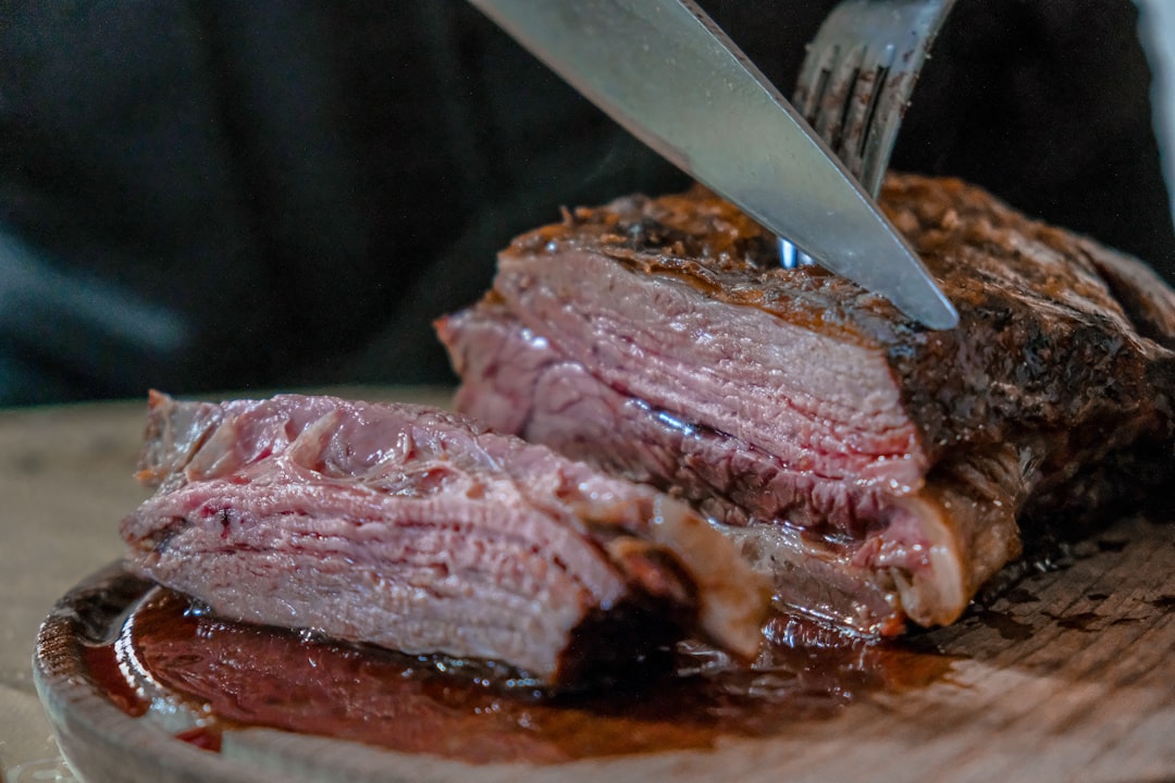 Roast beef on a wooden board with slicing knife and fork