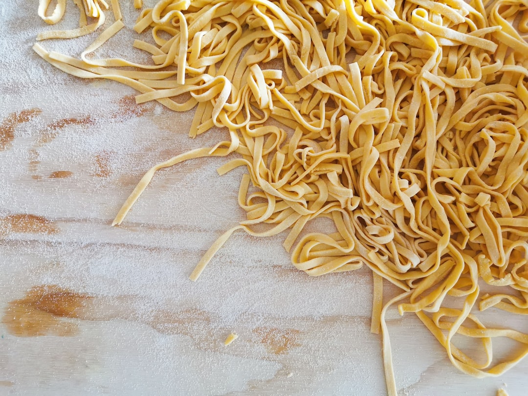 Loose fresh tagliatelle noodles on a floured wooden board