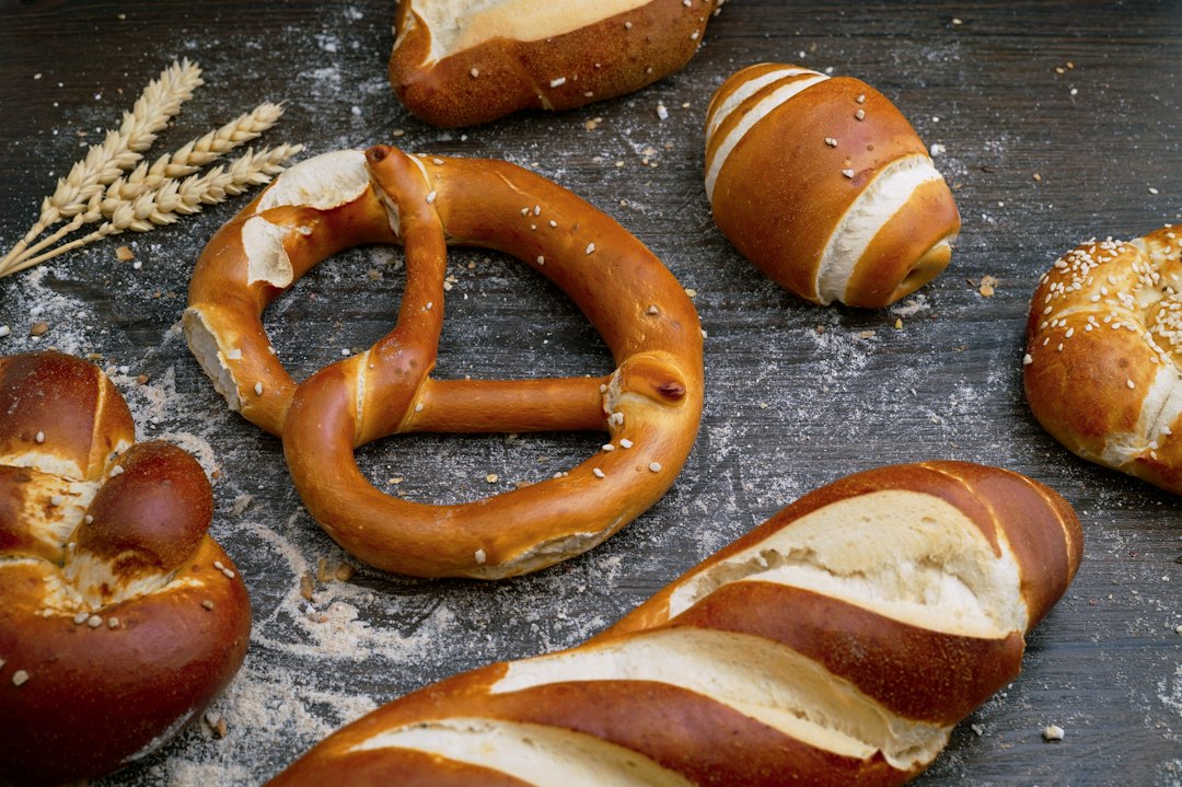 Freshly baked pretzels resting on a floured bench, one broken open to show the crumb