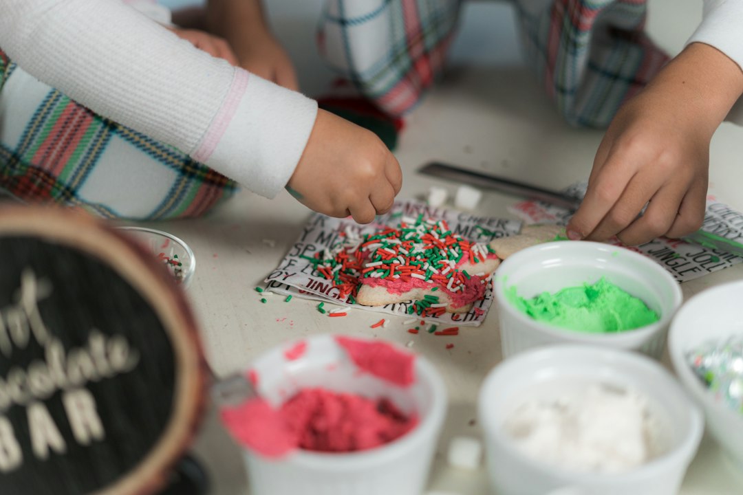 Children decorating cookies with sprinkles at a kitchen table