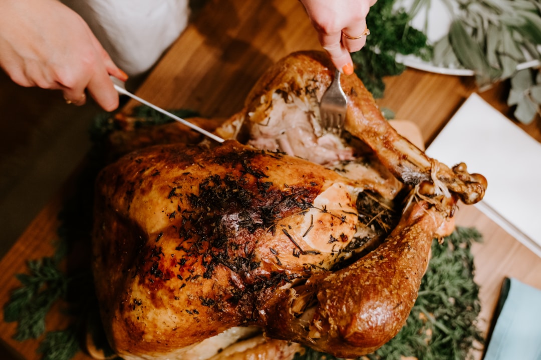 Hands carving a roasted turkey on a wooden table