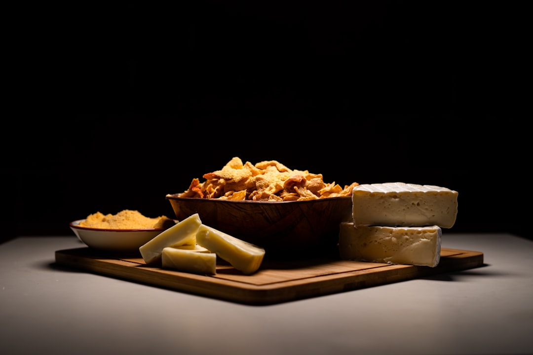 A bowl of shredded cheddar cheese next to blocks of cheese
