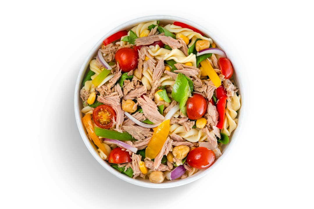 Shredded chicken salad bowl with cherry tomatoes, corn, and peppers
