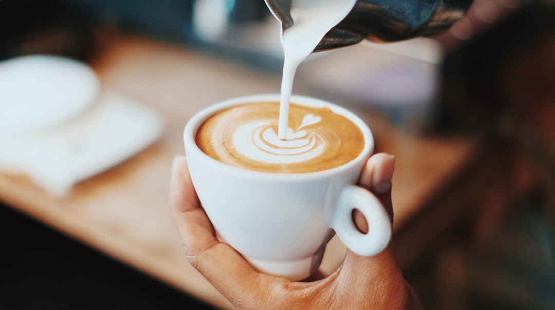Pouring latte art from a stainless steel milk pitcher