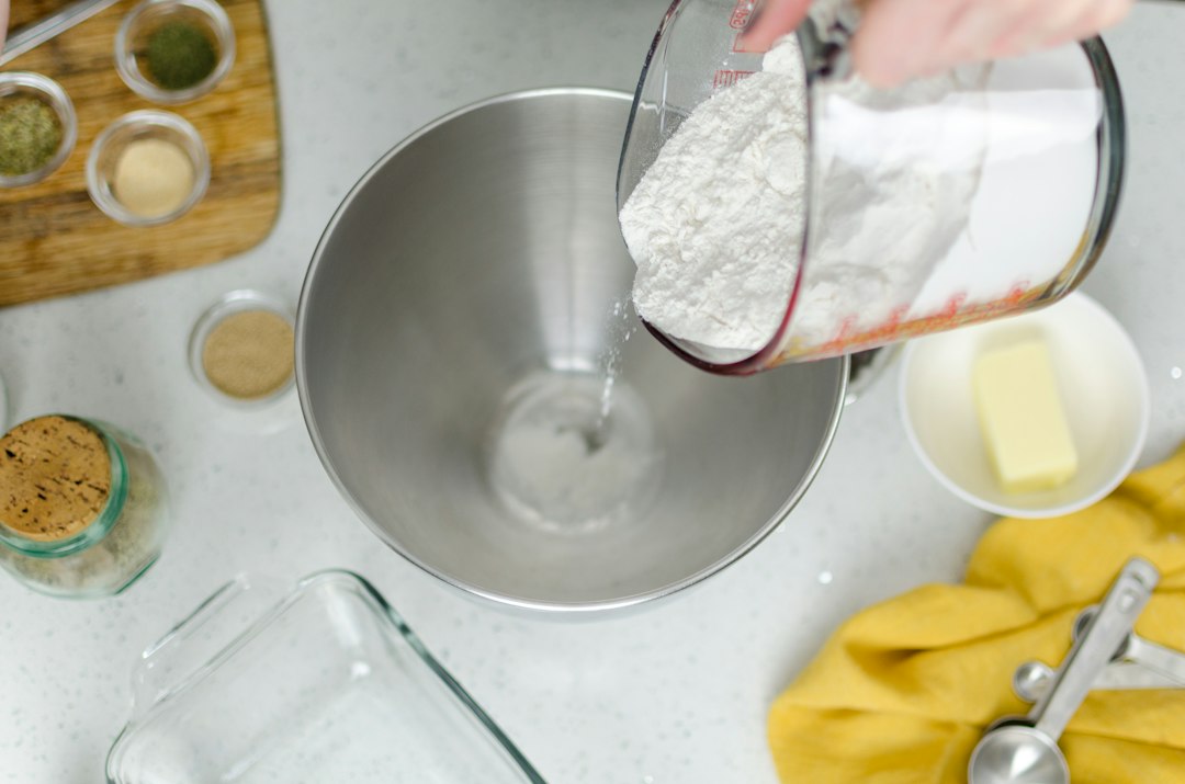 Pouring flour into a large metal mixing bowl