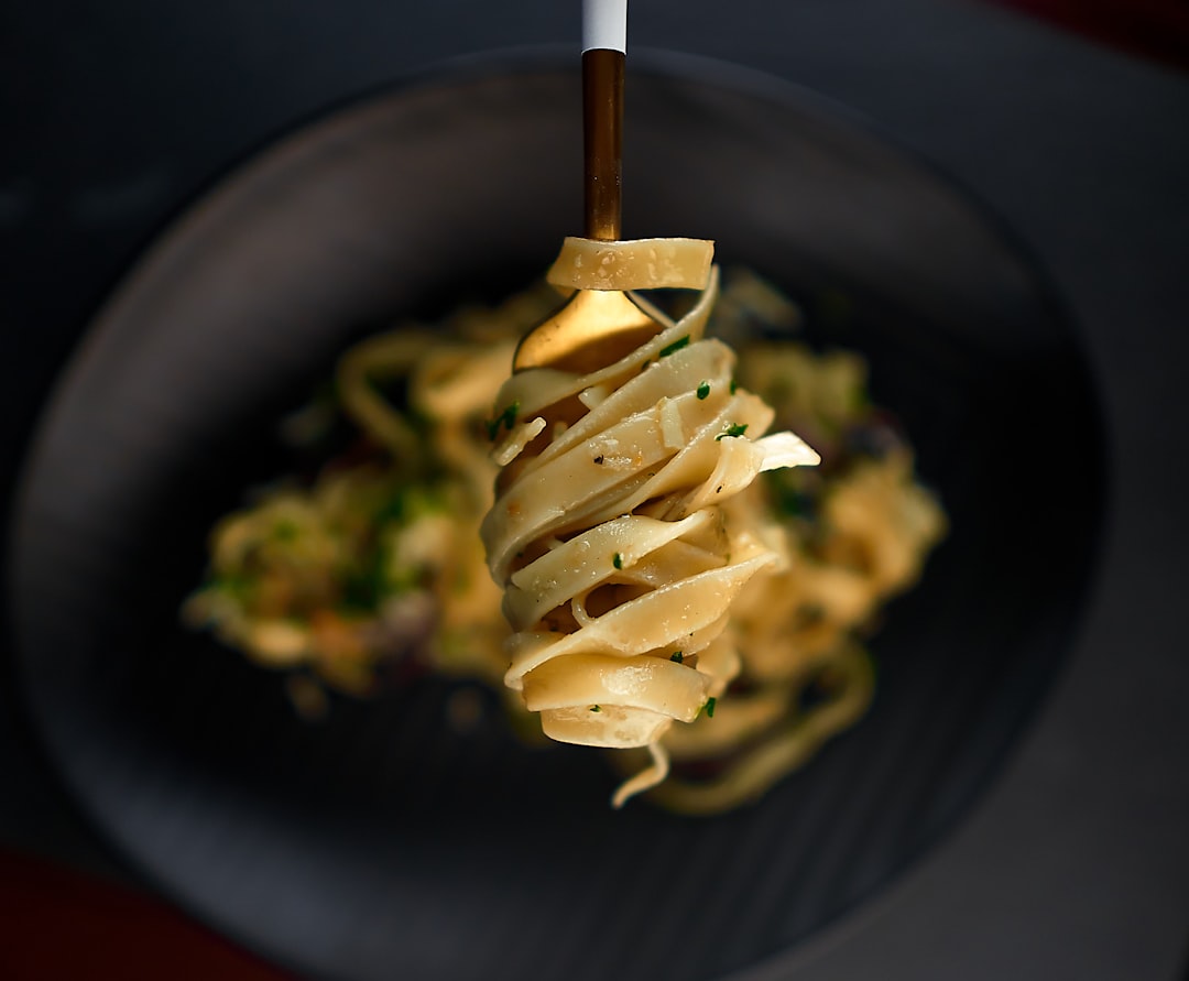 A fork lifting sauced fettuccine from a bowl at Sunday dinner