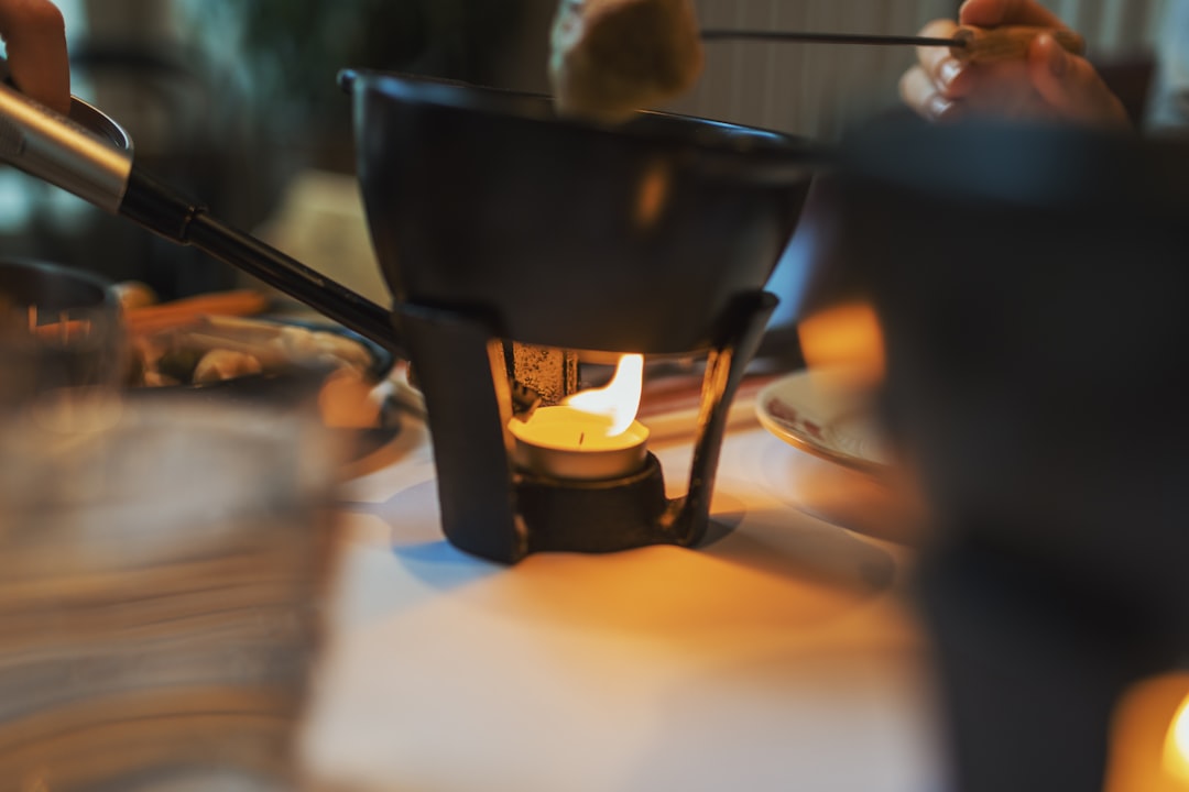 A cast iron pot of bubbling cheese fondue over a flame with bread ready for dipping