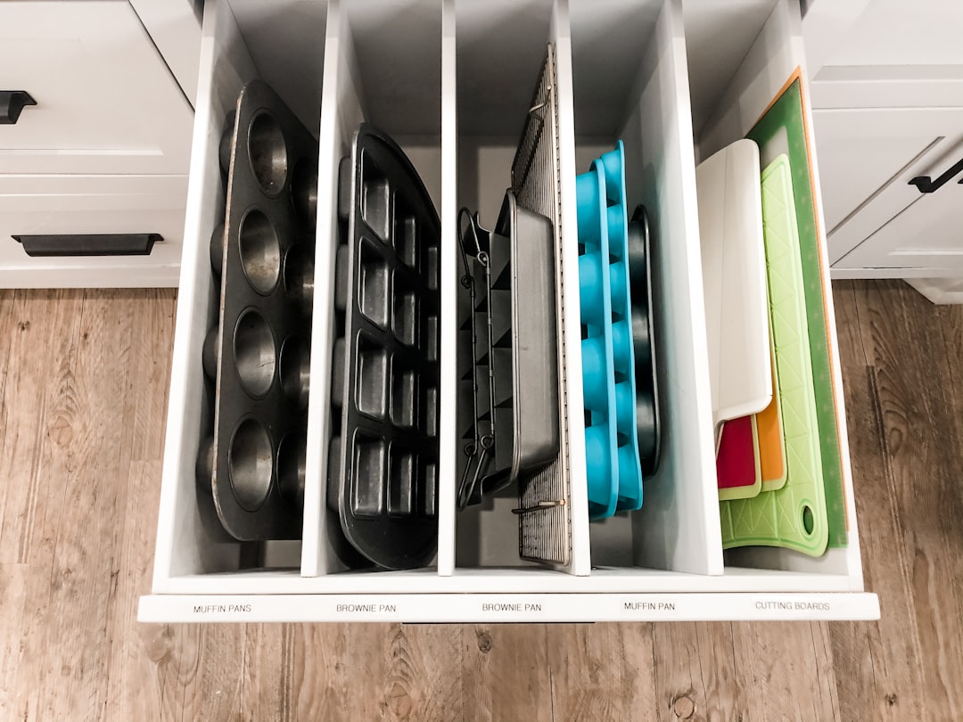 A drawer with bakeware and pans stored upright in divided slots
