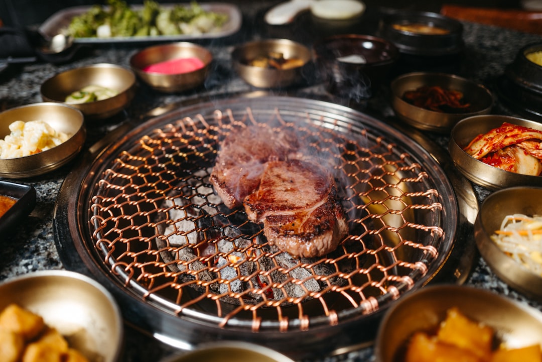 A tabletop grill sizzling with meat surrounded by small dishes, the same communal style as a raclette dinner
