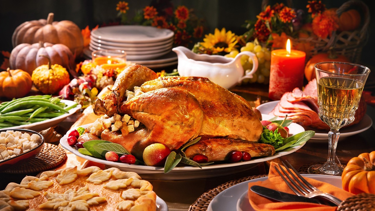 Roast turkey centerpiece on a Thanksgiving table with pumpkins, candles, green beans, and a gravy boat