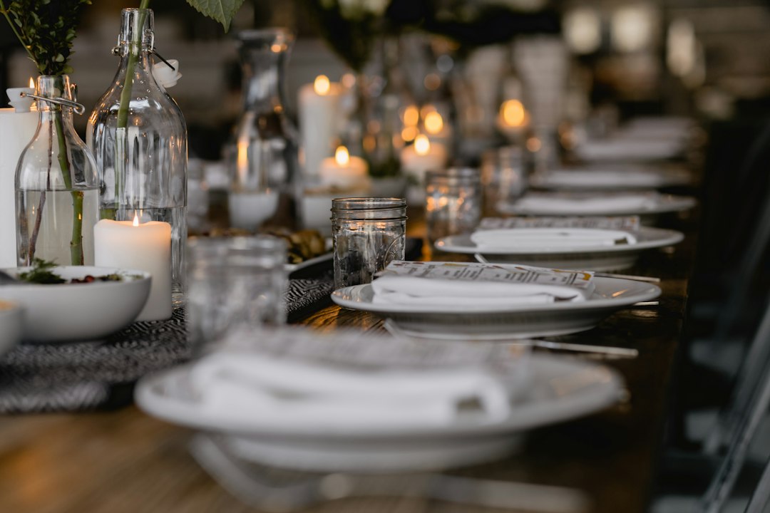 Holiday dinner table set with white plates, candles, and glassware