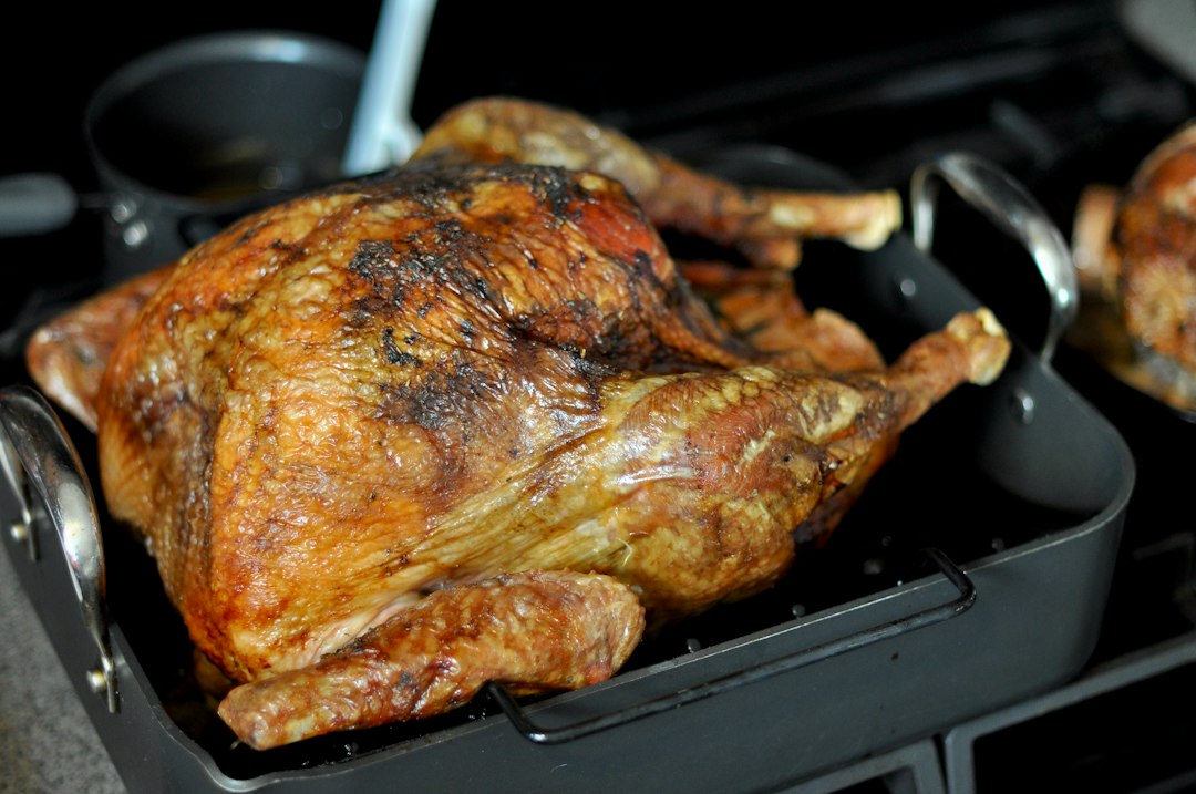 Roast turkey resting in its pan with rich juices collecting below