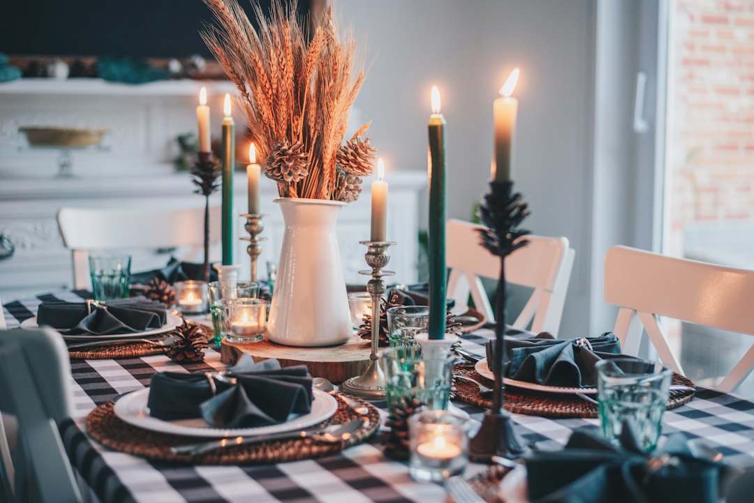 A fall dining table set with candles, wheat, and dark napkins, waiting for the carved bird