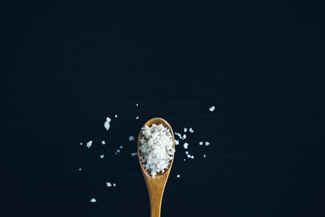 Hand seasoning a dish with salt from a shaker