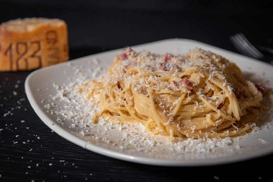 Spaghetti covered in a snowfall of grated hard cheese beside a Parmesan wedge