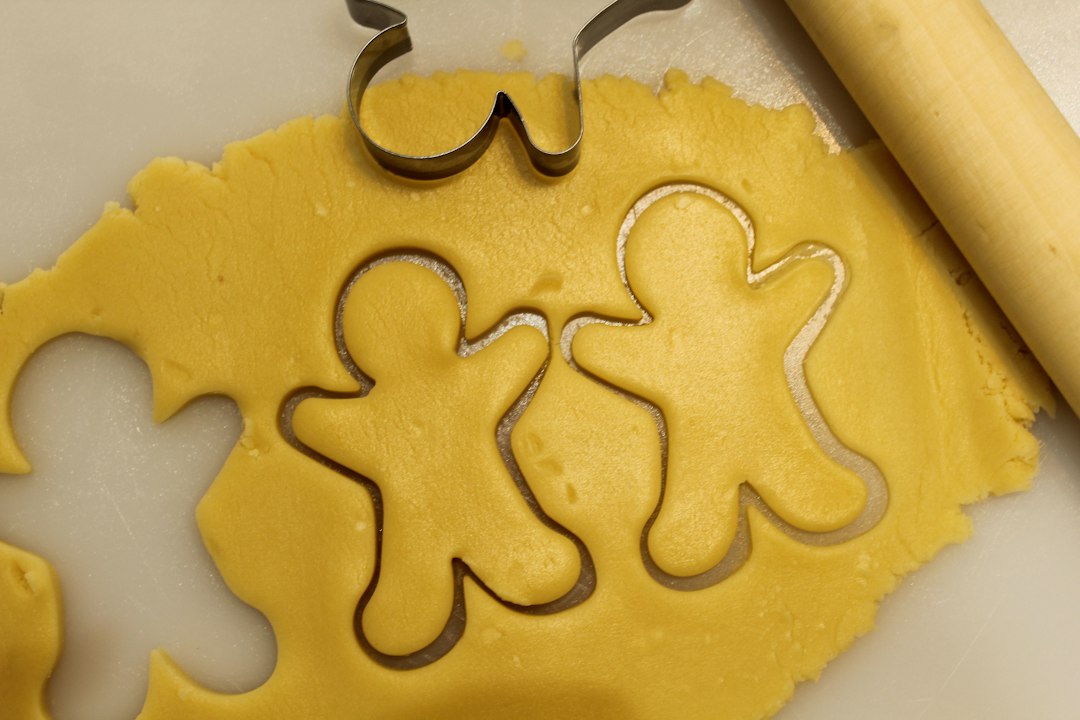 Sugar cookies and metal cutters arranged on a baking sheet