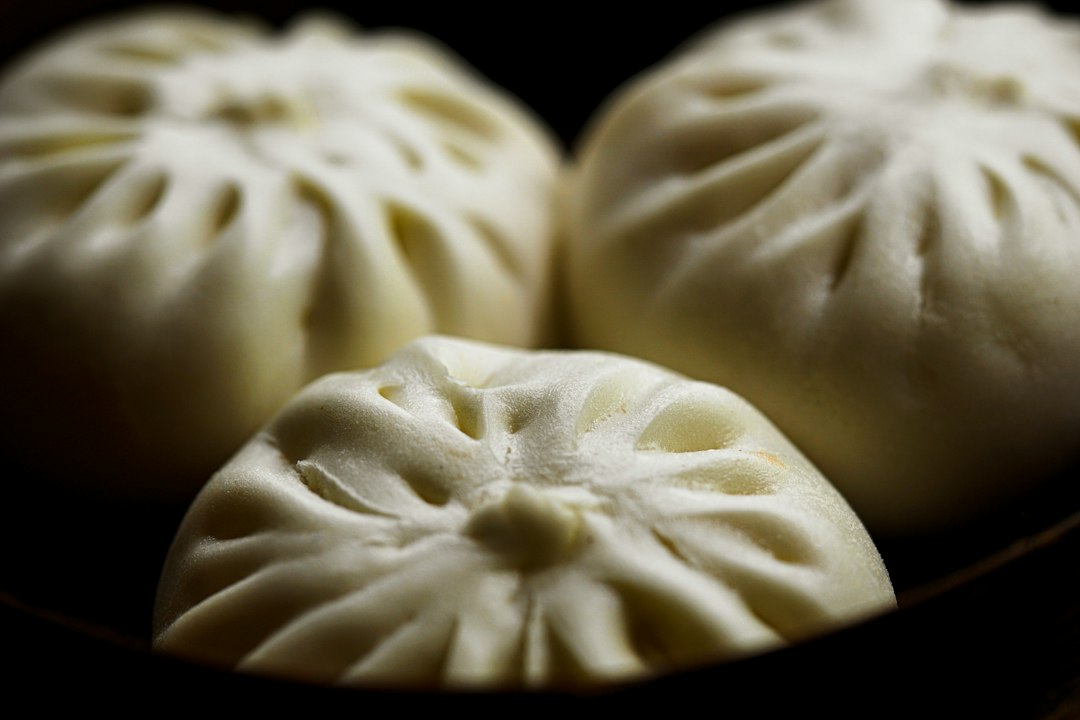 Three pale pleated steamed buns in close-up