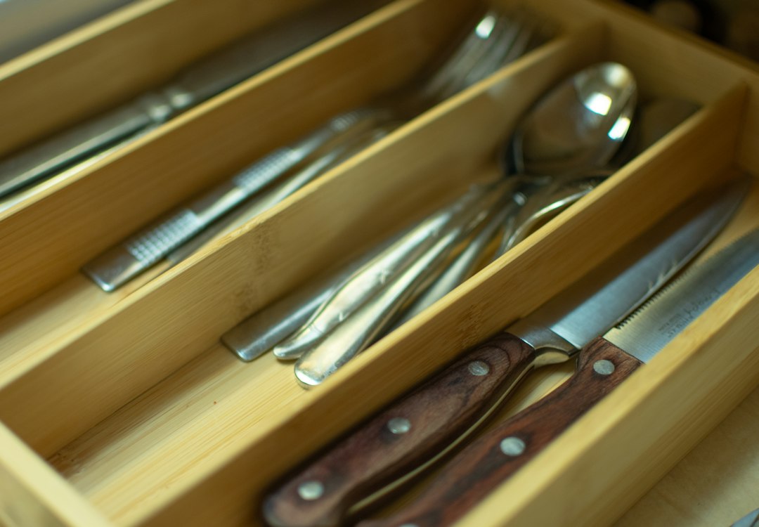 Close-up of a bamboo cutlery tray holding forks, spoons and knives in neat slots