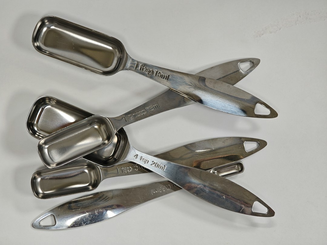 A pile of stainless steel measuring spoons and scoops
