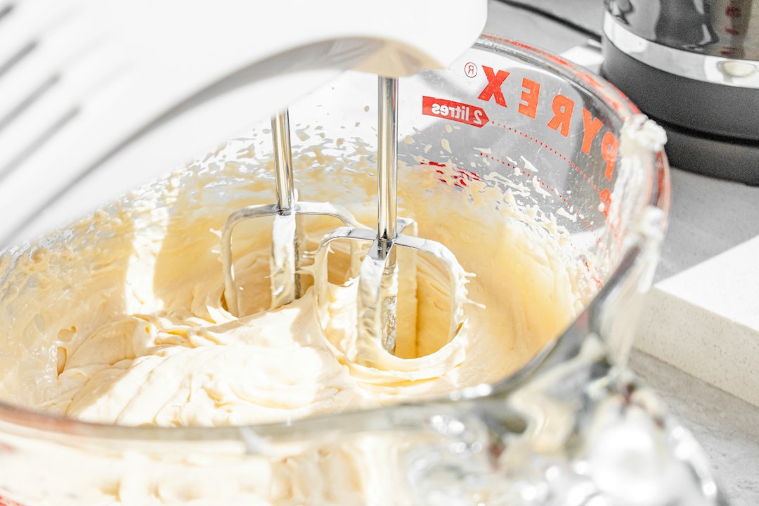 hand mixer beating cake batter in a glass bowl