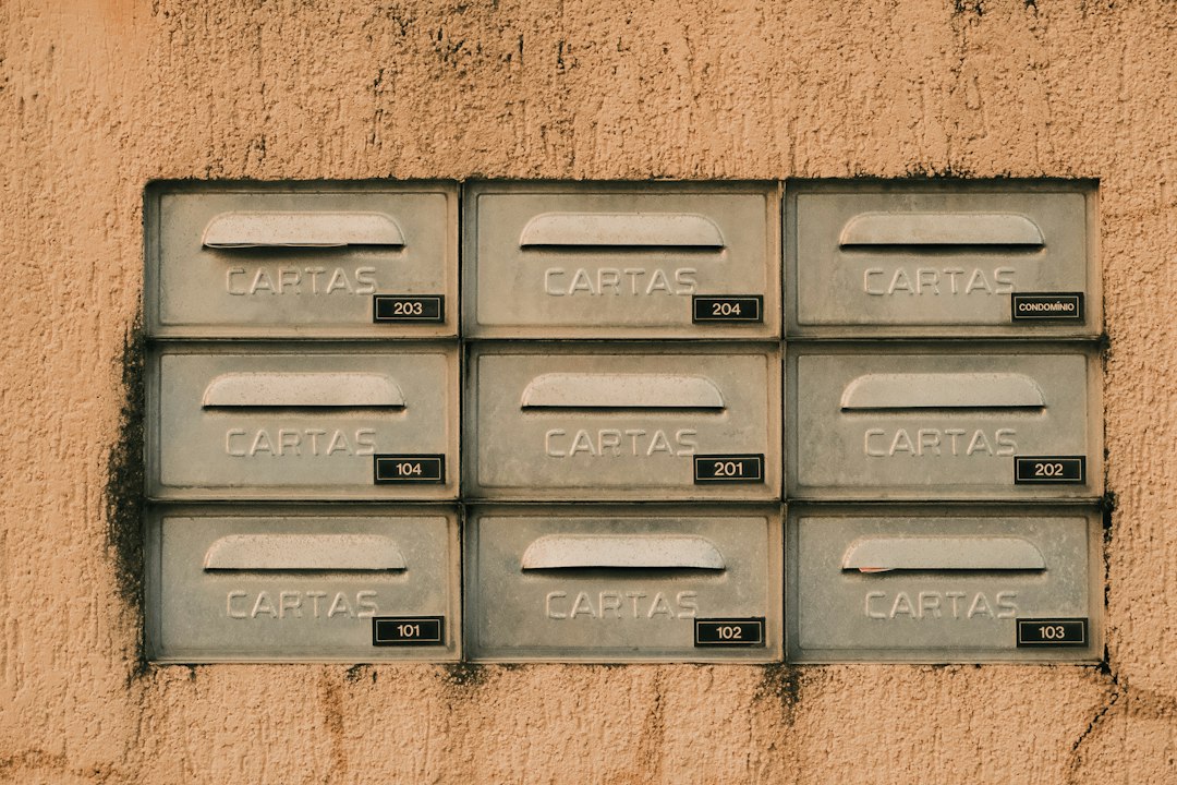 A grid of numbered metal mailboxes on a wall, each slot holding letters for a different household