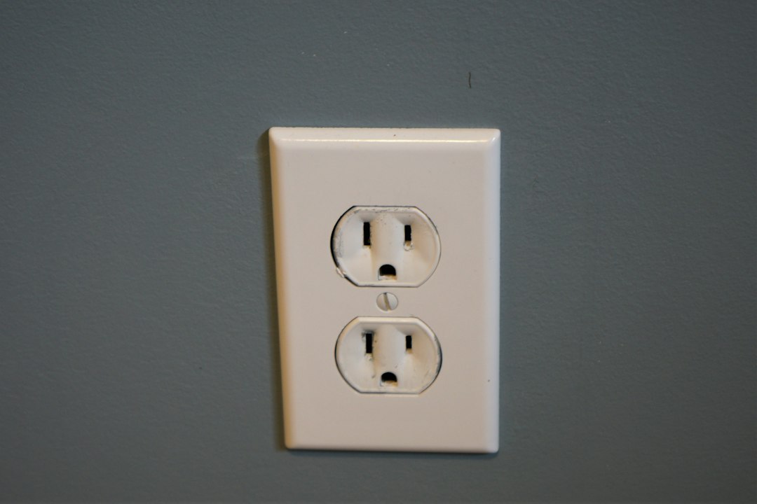 A white smart plug installed in a kitchen wall outlet