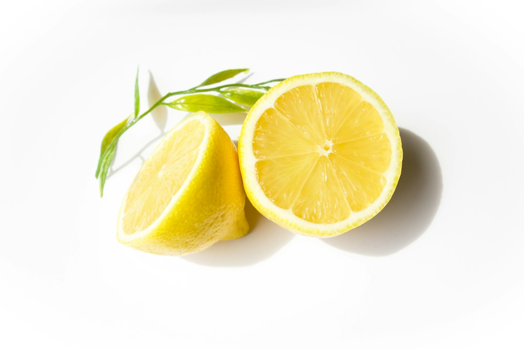 A halved lemon and a cut lemon face with a small green sprig