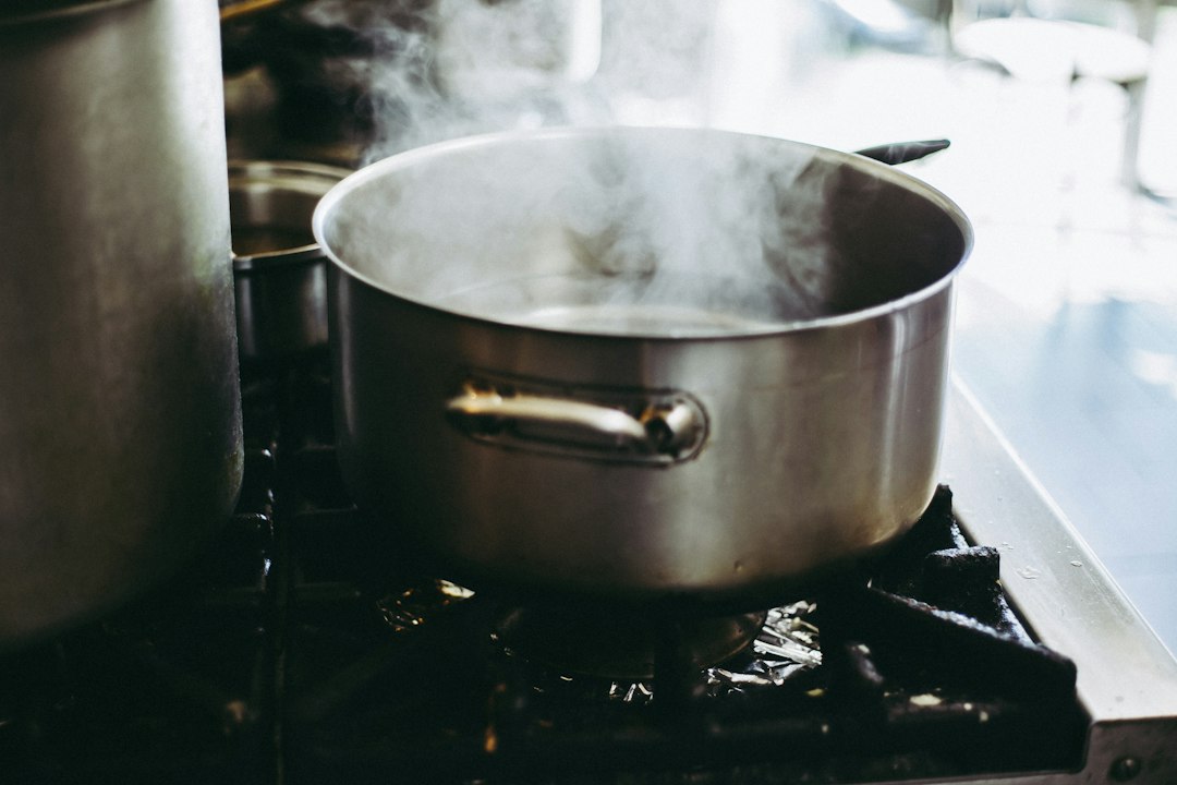 Stainless pot on a gas burner with steam rising from the open top
